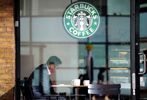 Ein Mann sitzt am Tisch in einem Starbucks-Café. Zurzeit hat die US-Kette in Deutschland 150 Filialen, ihr Ziel sind 500. (FOTO: DPA)