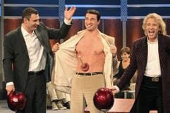 Wladimir Klitschko präsentiert am Samstag bei «Wetten, dass..?» in Basel eine Gummisaugglocke, die auf seinem Bauch klebt, während sein Bruder, der Boxer Vitali und Moderator Thomas Gottschalk daneben stehen. (Foto: dpa)