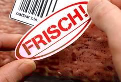 Auf eine Verpackung mit Hackfleisch wird ein Aufkleber mit der Aufschrift «Frisch» neben den Strich-Code mit der Aufschrift «haltbar bis ...». (Foto: dpa)