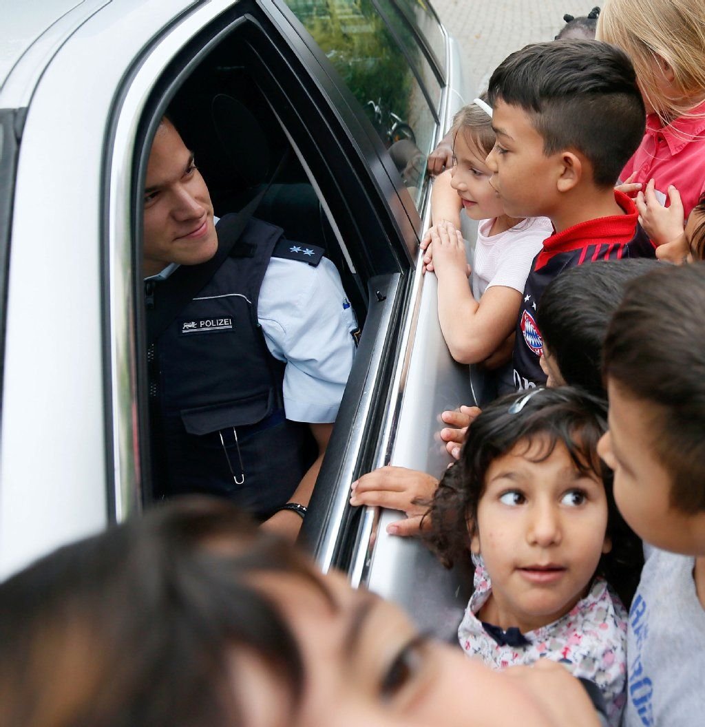 Kinder unterhalten sich mit einem Streifenpolizisten in einer Flüchtlingsunterkunft in Heidelberg.