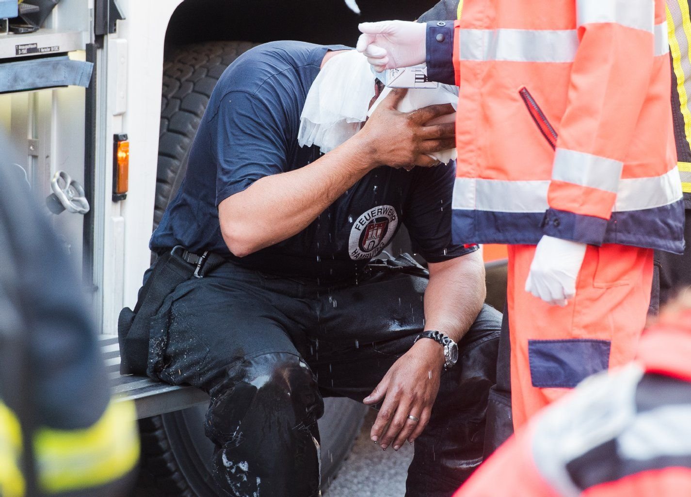Ein verletzter Feuerwehrmann kühlt sich mit Wasser.