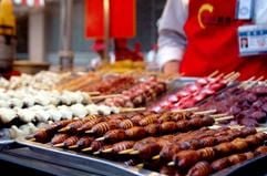 Raupen am Spieß und andere proteinreiche Leckereien bietet ein Verkäufer in einer Garküchenstraße in Peking an (Foto von Juni 2004). Vor dem Verzehr werden die Snacks in siedendem Öl frittiert. (Foto: dpa)