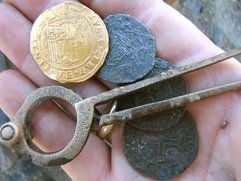 Eine spanische Goldmünze, drei portugiesische Silbermünzen und ein Zirkel zählen zu den Funden auf dem Meeresgrund an der Küste Namibias. Goldmünzen, Musketen und Kanonen: Der Fund eines rätselhaften Schiffswracks vor der Küste Namibias beflügelt die Fantasie. (Foto: dpa)