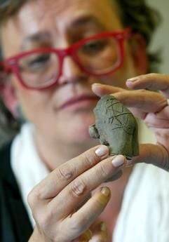 Die Landesarchäologin Judith Oexle hält am Donnerstag (21.08. 2003) im Landesamt für Archäologie in Dresden-Klotzsche die älteste männliche Tonfigur Mitteleuropas in den Händen. Der außergwöhnliche Fund wurde am Dienstag (19.08.2003) bei Zschernitz im Landkreis Delitzsch bei Grabungsarbeiten an einer Erdgastrasse entdeckt. Die Figur wurde vom Landesamt - nach dem Fundort - «Adonis von Zschernitz» genannt. Der teils tätowierte Torso wurde auf 5000-4900 vor Chr. in die jungsteinzeitliche Bandkeramik-Kultur datiert. (Foto: dpa)