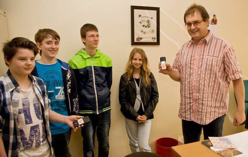 Finanzbeamter Ralf Neuner klebt ein Pfandsiegel auf das Handy eines Schülers.