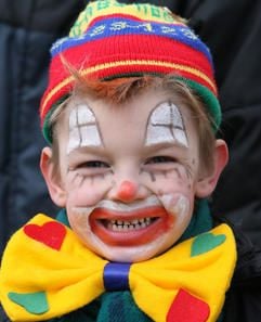 Ein Kind mit bunt geschminktem Gesicht steht beim Rosenmontagsumzug in Köthen am Straßenrand. (Foto: dpa)