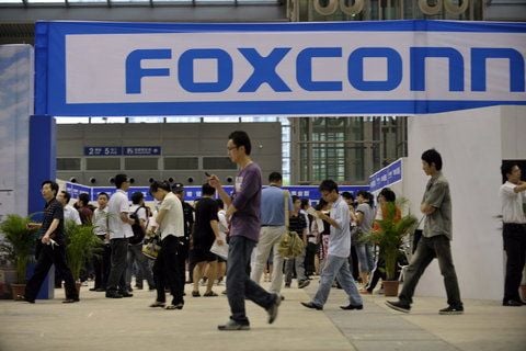 Angestellte eines Foxconn-Werkes in Shenzen passieren das Logo des Unternehmens (Foto vom 22.05.2010). Nach gewaltsamen Unruhen unter seinen Arbeitern hat der weltgrößte Elektronikhersteller Foxconn am Montag (24.09.2012) eines seiner Werke in China schließen müssen. (FOTO: DPA)