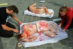 Aktivisten der internationalen Tierrechtsorganisation PETA werden am Mittwoch (06.09.2006) auf dem Neuen Markt in Rostock in große Fleischschalen unter durchsichtige Folie verpackt, damit sie wie im Supermarkt verkauftes Menschenfleisch aussehen. (Foto: dpa)