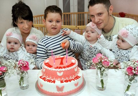 Mit seinen Schwestern, den Geburtstagskindern Jasmin, Sophie, Laura und Kim (l-r.) und den Eltern Janett und Marcus Mehnert sitzt der sechsjährige Bruder Lucas (m.) vor einer großen Geburtstagstorte (FOTO: DPA)