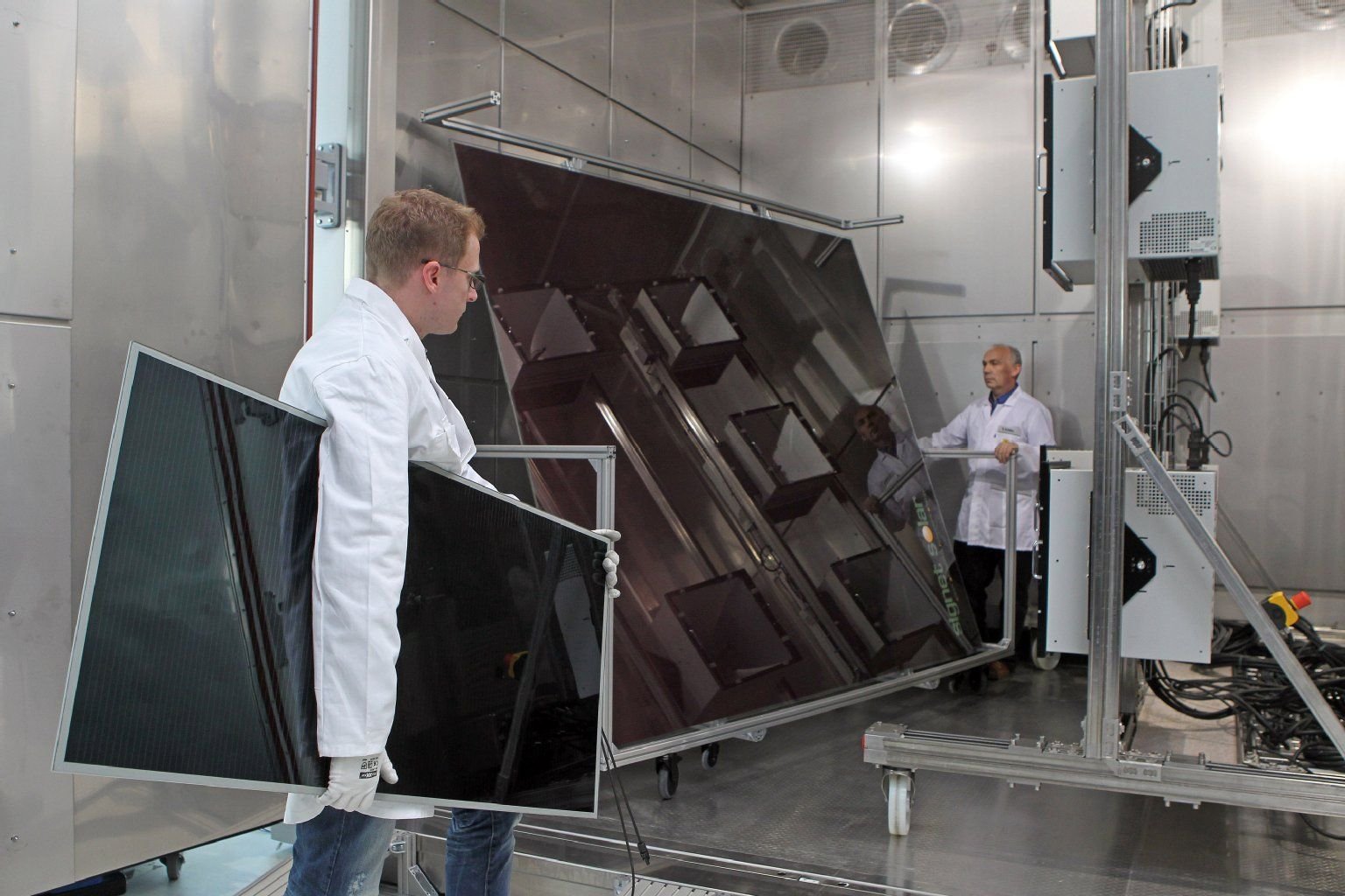 Einen Bewitterungsversuch an Solarmodulen in einer Klimakammer bereiten Sascha Dietrich (hinten) und Ralf Schäfer, Mitarbeiter des Fraunhofer-Centers für Silizium-Photovoltaik CSP, in Halle (Saale) vor.