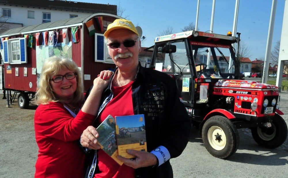 Barbara und Dieter Christian Ochs zeigen sich vor ihrem Traktor mit Wohnwagenanhänger, mit dem sie auch zur Buchmesse und zurück gefahren sind.