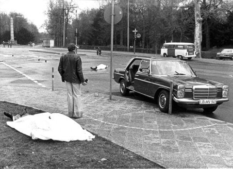 Der Tatort mit den zugedeckten Leichen von Siegfried Buback (vorne links) und seines Fahrers sowie der Dienstwagen des Generalbundesanwaltes in Karlsruhe (07.04.1977). (FOTO: DPA)