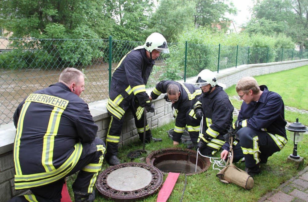 Feuerwehrleute aus Gatersleben schließen einnen Schieber des Kanalsystems zur Straßenentwässerung und pumpen Regenwasser ab.