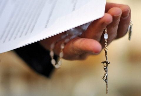 Ein Priester hält einen Rosenkranz und eine bischöfliche Erklärung zu den Missbrauchsfällen durch Jesuiten-Pater in der Hand. (FOTO: DPA)