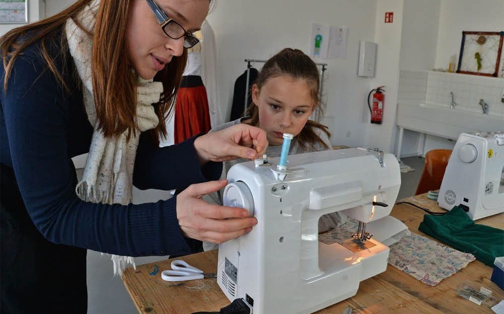 Charlotte van Lie zeigt an der Nähmaschine, wie es richtig geht.