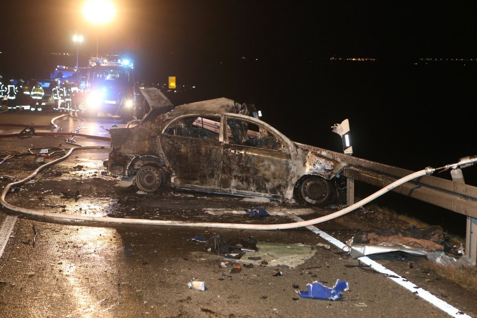 Einsatzkräfte stehen nach einem schweren Verkehrsunfall am Montagabend auf der Bundesstrasse 2 zwischen Gera und Zeitz an einem ausgebrannten Auto.