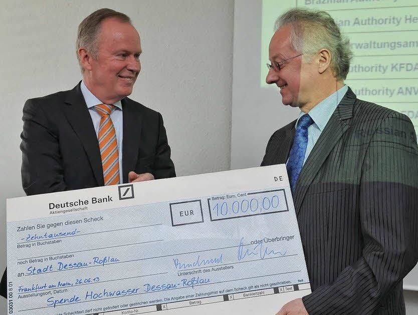 Hartmut Erlinghagen, Chief Administrative Officer der Merz GmbH & Co.KG, überreicht während der Feierstunde zum Firmenjubiläum einen symbolischen Spendenscheck für die Milderung der Hochwasserschäden an Dessau-Roßlaus Oberbürgermeister Klemens Koschig.
