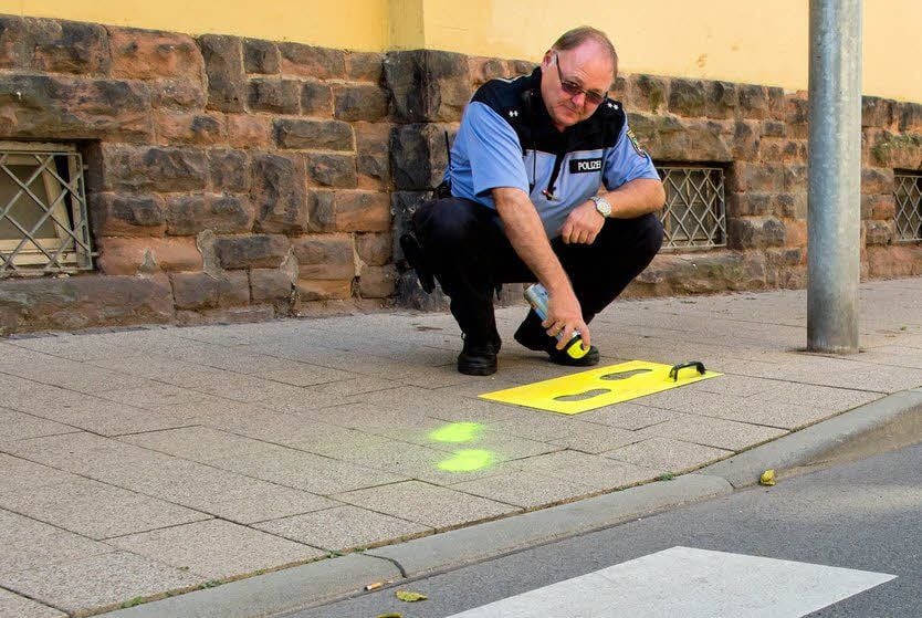 Polizeibeamter Lothar Eckert sprüht in der Christianenstraße in Merseburg gelbe Füße als Orientierung für einen sicheren Schulweg auf den Boden auf.