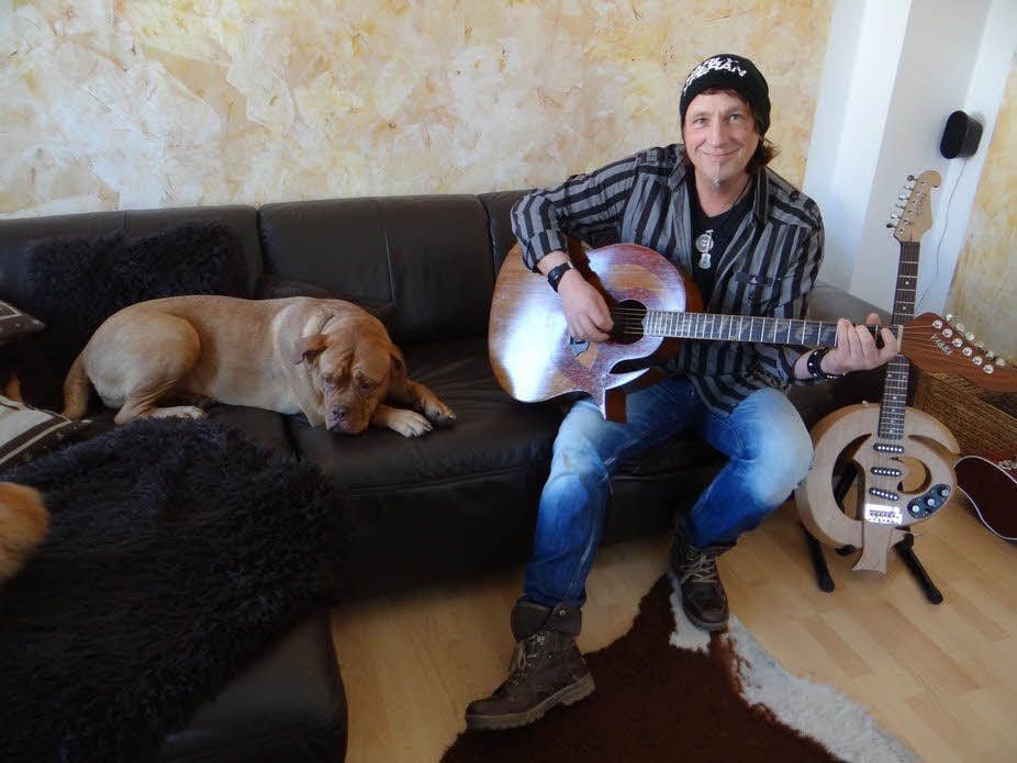 Manchmal nimmt sich Carly Peran eine der beiden Gitarren, die Fans ihm zum 50. Geburtstag selbst gebaut haben, und spielt Familienhund Berta etwas vor.