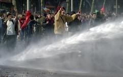 Demonstranten stehen am Montag (24.03.2003) im Strahl eines Wasserwerfers in der Hamburger Innenstadt. Während einer Schülerdemonstration gegen den Krieg im Irak kam es zu Ausschreitungen. (Foto: dpa)