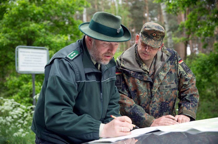 Rene Bruschke (links) vom Bundesforstamt Mittelelbe und Standortfeldwebel Mario Reihs betrachten den Grenzverlauf des Standortübungsplatzes in der Annaburger Heide auf einer Karte.