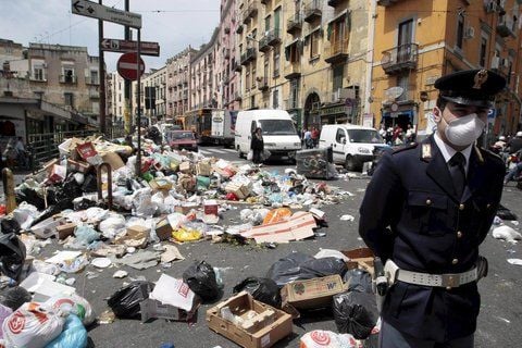 Mit Mundschutz läuft ein Polizist an Müllbergen in einer Straße in Neapel vorbei. Bereits 2008 drohte Neapel im Müll zu ersticken. (FOTO: DPA)
