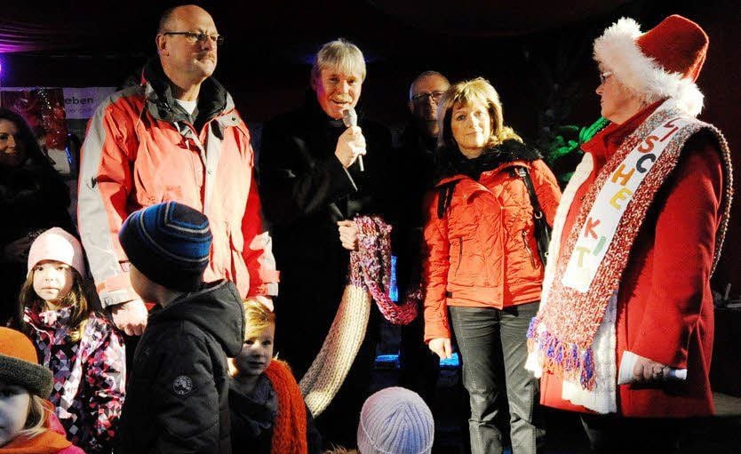Rainer vor der Straße (am Mikrofon), der den Schal ersteigert hat, mit weiteren Geldspendern und Eislebens Oberbürgermeisterin Jutta Fischer (r.).
