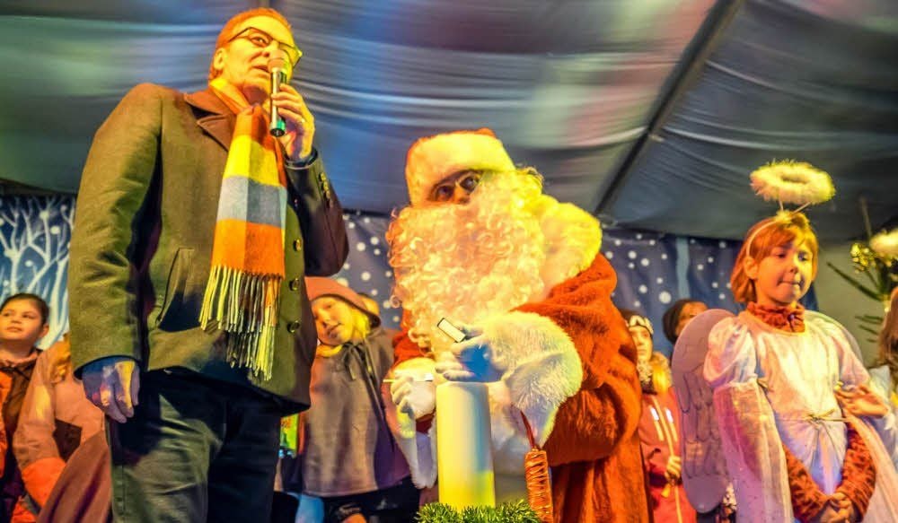 Franz Neise, Chef des Gewerbevereins, und der Weihnachtsmann, der hier gerade eine Kerze entzündet als symbolischen Akt der Eröffnung.