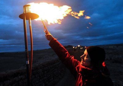 Emma Spence entzündet eine Fackel auf dem Hadrian's Wall in Northumberland in Nordengland. Freiwillige bildeten die 135 km lange «Linie des Lichts». (FOTO: DPA)