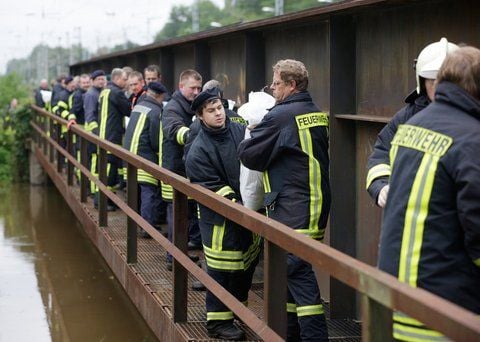 Feuerwehrleute werfen sich am Mittwoch auf einer Eisenbahnbrücke in Elsterwerda am Fluss Schwarze Elster Sandsäcke zu. (FOTO: DPA)