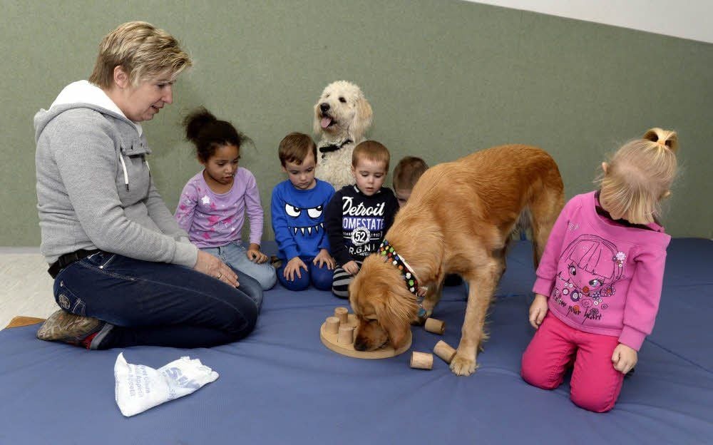 Kita-Leiterin Constanze Stock und die Kinder spielen mit Balu ein Zählspiel.