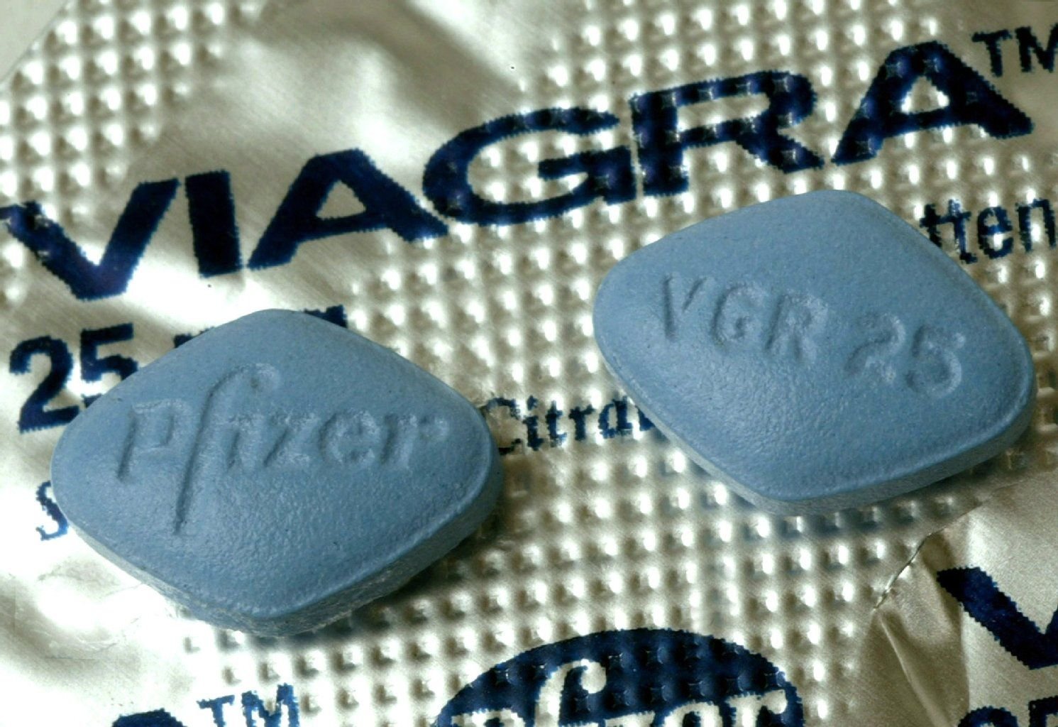 Zwei Tabletten Viagra liegen auf der Medikamentenverpackung.
