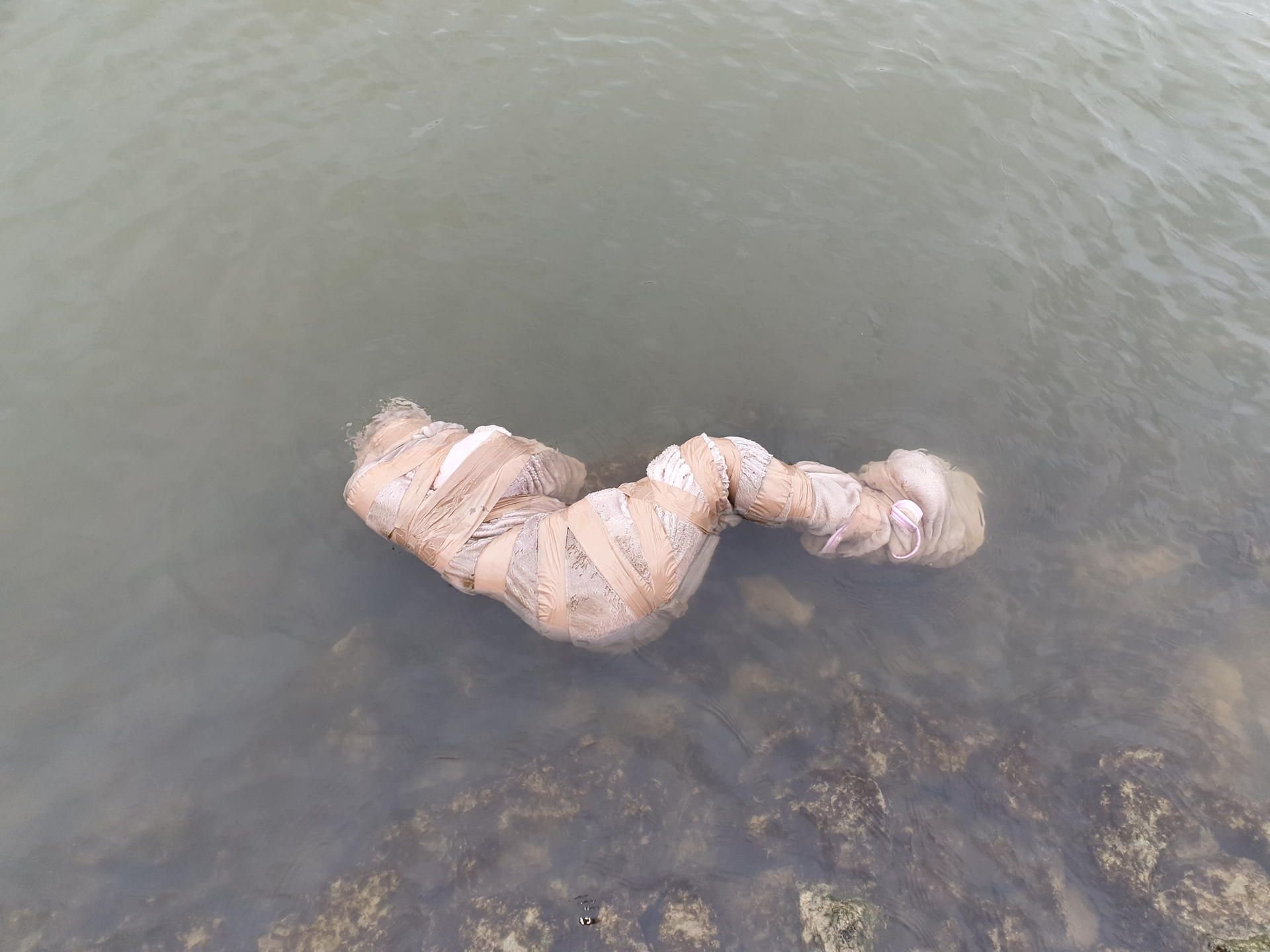 Eine in eine Decke gewickelte und mit Klebeband verschnürte, lebensecht wirkende Puppe liegt am Samstag im Wesel-Datteln-Kanal in Marl.
