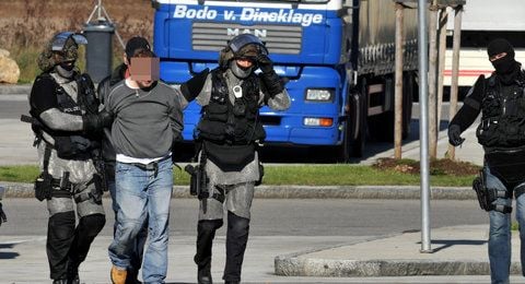 Ein Lastwagenfahrer wird am Mittwoch auf der Raststätte in Vaterstätten bei München (Oberbayern) von Polizisten abgeführt. (FOTO: DPA)