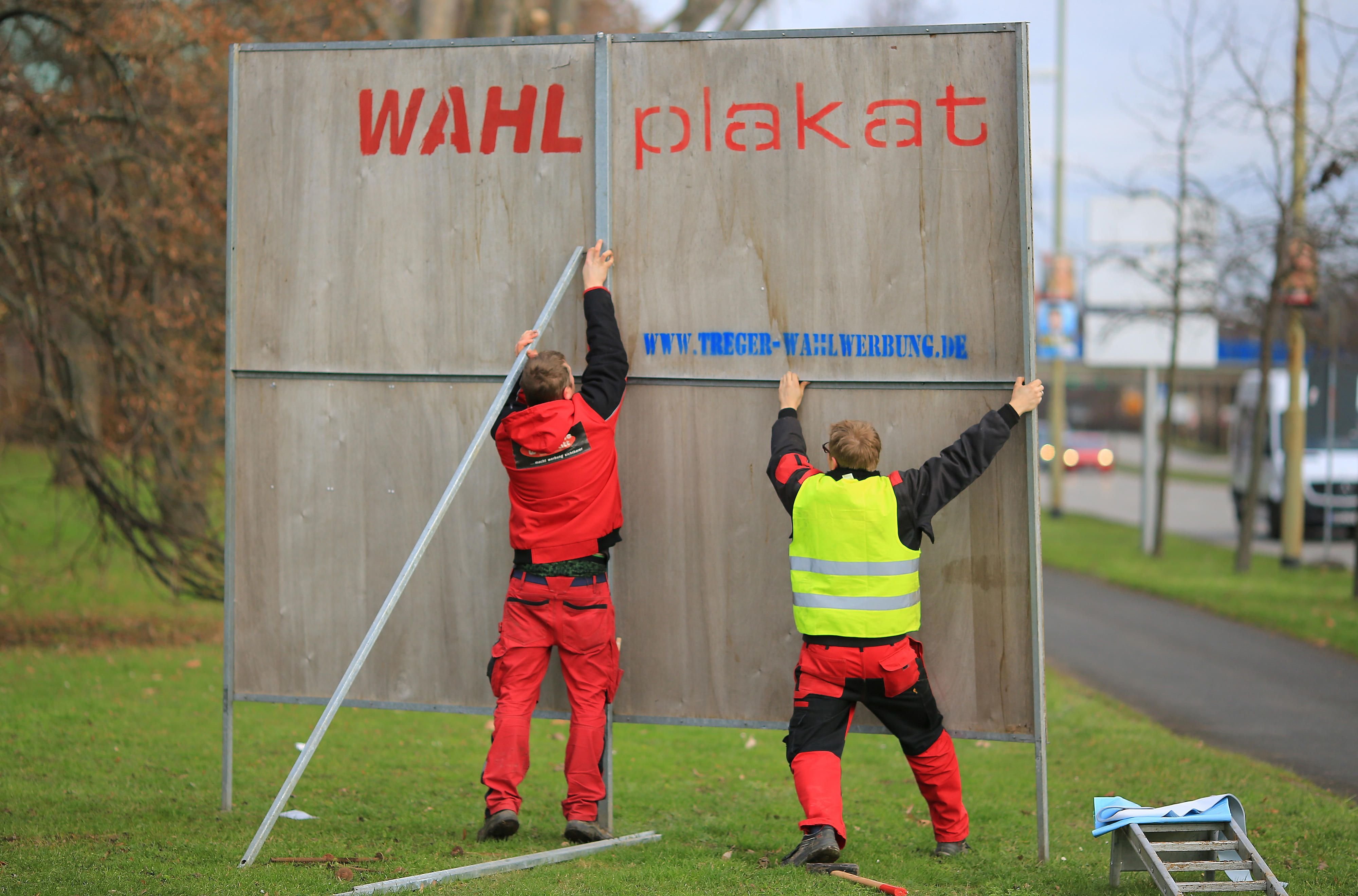Mitarbeiter einer Werbefirma stellen ein Wahlplakate auf.