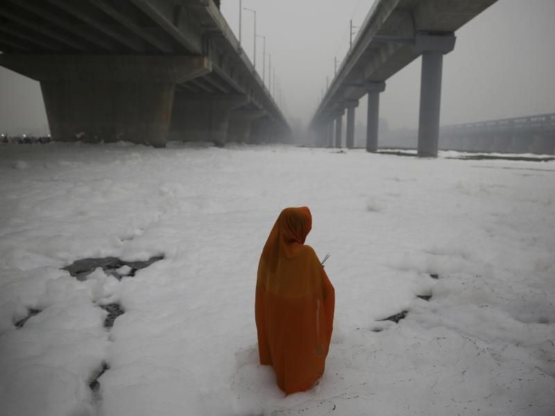 Eine hinduistische Gläubige führt während des Chhath Puja Festival ein Ritual im von Chemikalienschaum bedeckten Yamuna Fluss durch. Foto: Altaf Qadri/AP/dpa