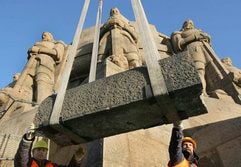 Auf dem 91 Meter hohen Völkerschlachtdenkmal in Leipzig lassen die Steinmetze Friedmar Triebler (r.) und Klaus-Dieter Witt einen rund zwei Tonnen schweren Brüstungsstein mit einem Kran wegheben. (Foto: dpa)
