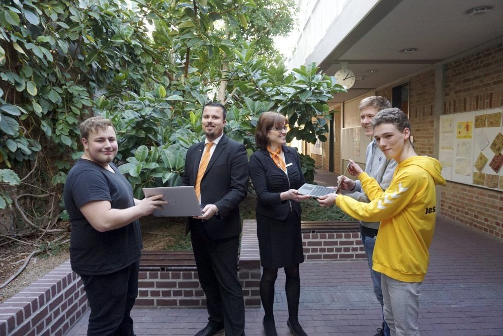 Rico Lange und Silke Reichow von der Volksbank Elsterland überreichen den Gymnasiasten Ole Berthold, Matteo Stelbrink und Johannes Kawalle (v.l.) die neuen Notebooks, die dank einer Spende gekauft werden konnten.