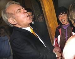 Bundespräsident Johannes Rau verzieht am Mittwoch (23.06.2004) beim Besuch des Jugendprojektes Soziale Grüne Landscheune in Rohlsdorf (Landkreis Prignitz) das Gesicht bei dem festen Händedruck einer Mitarbeiterin. In dem Projekt betreut ein Verein benachteiligte und straffällig gewordene Jugendliche. Unter Anleitung sanieren die jungen Leute alte Fachwerkhäuser im Ort, arbeiten im Ökolandbau oder auf dem Arche-Hof der Landscheune. Bei seiner Prignitz-Visite hatte der Bundespräsident auch den Schreibgerätehersteller Cleo in Bad Wilsnack besucht. (Foto: dpa)