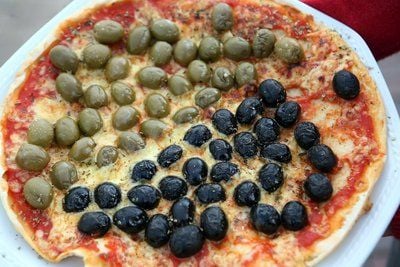 Eine Pizza, mit schwarzen und grünen Oliven belegt (FOTO: DPA)
