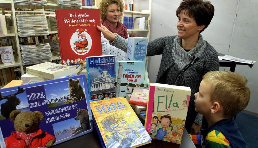 Bibliotheksmitarbeiterin Grit Gennat (2.v.r.) freut sich über die finnischen Bücher, die Christine Hermsdorf und ihr Sohn Georg gebracht haben.