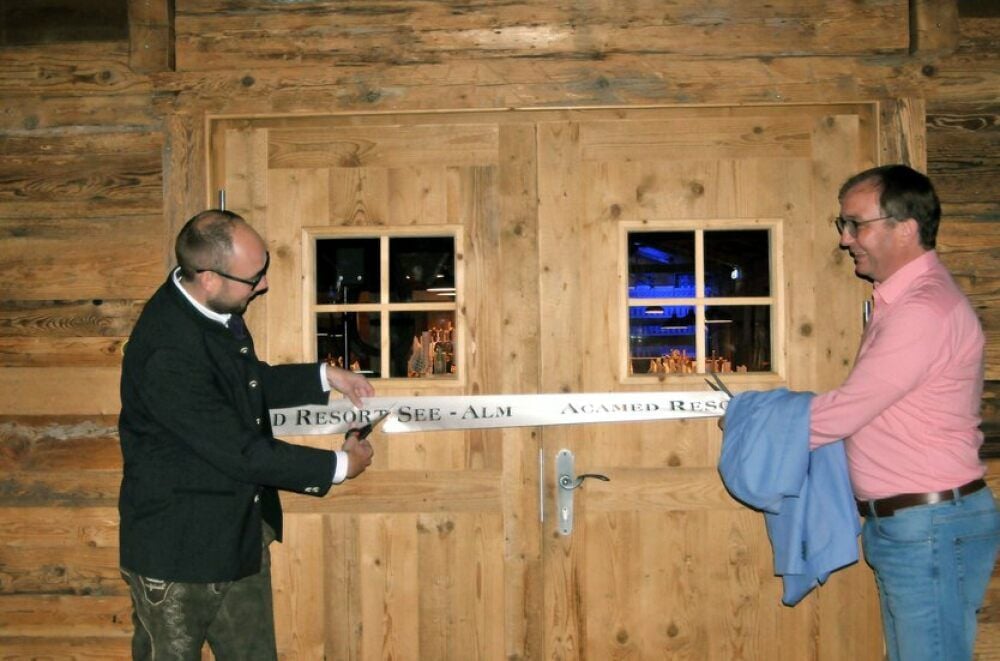 Hotel-Chef Frank Wyszkowski (li.) und Landrat Markus Bauer schneiden zur Eröffnung der See-Alm das symbolische Band durch.