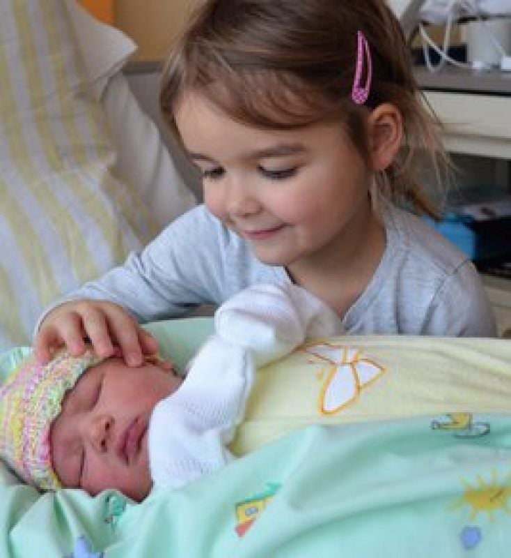 Die vierjährige Marta freut sich über ihre neugeborene Schwester Lucie.