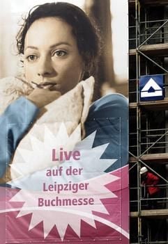 Ein Bauarbeiter auf einem Gerüst schaut auf ein Plakat mit der Aufschrift "Live auf der Leipziger Buchmesse", das am Montag (15.03.2004) an einem Gebäude in Leipzig hängt. Am 25.03.2004 beginnt in Leipzig die traditionelle Buchmesse. Bis zum 28.03.2004 werden mehr als 2.000 Verlage und Editionen aus 29 Ländern auf der Neuen Messe ihre Programme und Neuerscheinungen vorstellen. Themenschwerpunkte sind in diesem Jahr Buchproduktionen aus Mittel- und Osteuropa, Reiseliteratur, Hörbücher sowie Kinder- und Jugendbücher und Comics. (Foto: dpa)