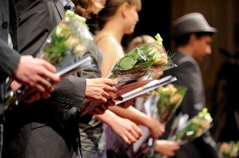 Teilnehmer einer Jugendweihe halten auf einer Bühne Bücher und Blumen in den Händen. (FOTO: DAPD)
