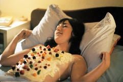 Die Kellnerin Eden (Charlotte Roche) liegt in dem neuen Kinofilm «Eden» mit Creme und Beeren garniertem Oberkörper im Bett (undatierte Filmszene). (Foto: dpa)