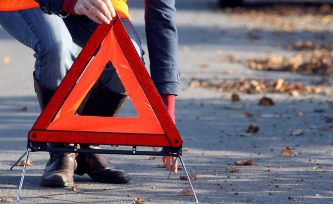 An einer Unfallstelle wird ein Warndreieck aufgestellt.