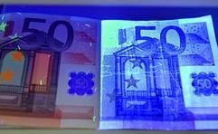 Unter UV-Licht liegen in der Deutschen Bundesbank in Frankfurt/Main eine echte (l.) und eine gefälschte 50 Euro-Note. (Foto: dpa)