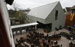 Geladene Gäste sitzen am Samstag bei der Einweihung vor einem der drei neuen Museen auf der Weltkulturerbe-Insel Reichenau im Bodensee (Baden-Württemberg). (Foto: dpa)