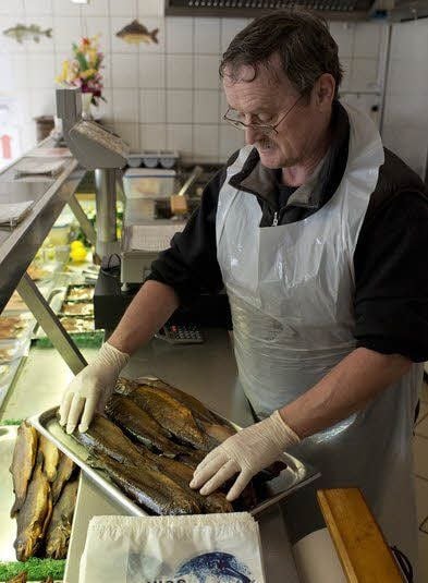 Mitarbeiter Andreas Richter bietet frisch geräucherte Forellen an.